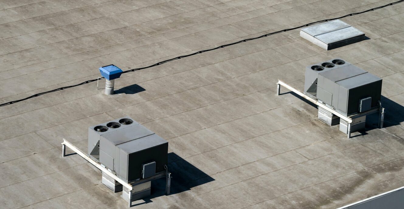 The external units of the commercial air conditioning and ventilation systems are installed on the roof of an industrial building.
