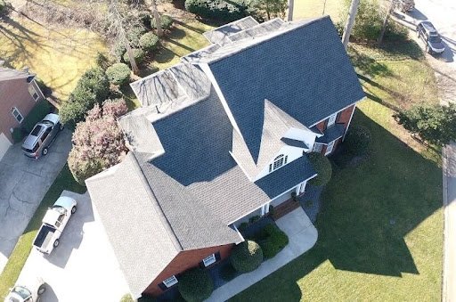 Aerial view of residential home in Greenville, South Carolina showing dark asphalt shingle roof replacement and light-colored siding with manicured lawn