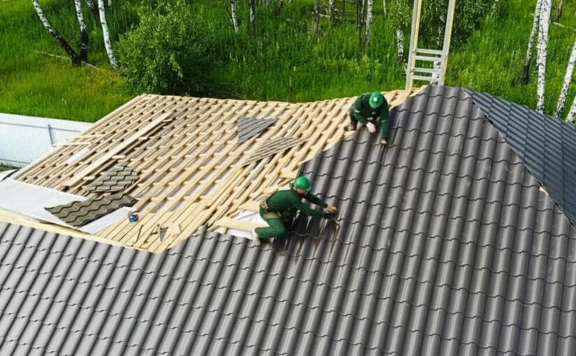 Roofers in green safety gear installing dark shingles on a residential roof under construction in Greenville, South Carolina