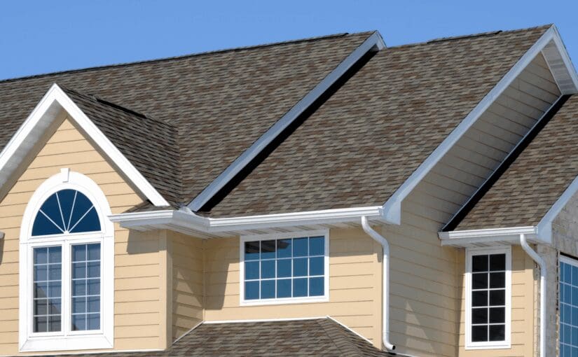 Modern two-story home with gabled roof, asphalt shingles, cream siding, white trim, and multiple windows against clear blue sky